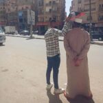 لقطة إنسانية تهز القلوب في الفيوم: شاب يظلل والده من الشمس بلوحة كرتونية