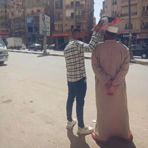 لقطة إنسانية تهز القلوب في الفيوم: شاب يظلل والده من الشمس بلوحة كرتونية
