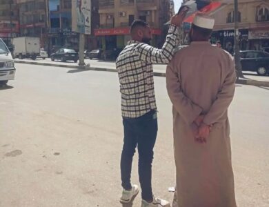 لقطة إنسانية تهز القلوب في الفيوم: شاب يظلل والده من الشمس بلوحة كرتونية