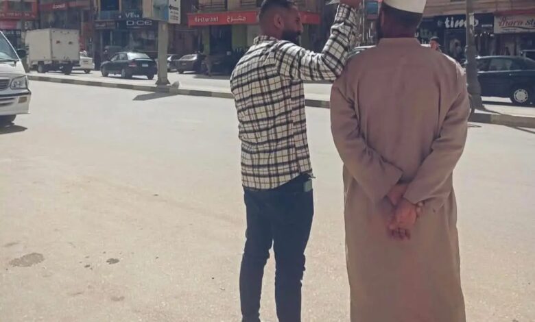 لقطة إنسانية تهز القلوب في الفيوم: شاب يظلل والده من الشمس بلوحة كرتونية